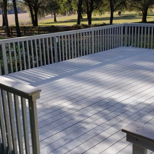 Multi-level white painted deck with built-in bench seating and white railing system in outdoor setting