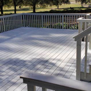 Wide angle view of freshly painted white deck with partial railing and support posts visible