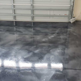 Glossy metallic epoxy garage floor reflecting overhead garage door, showing gray and white swirled pattern
