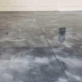 Metallic epoxy garage floor with cloudy gray pattern showing high reflectivity and visible floor seams