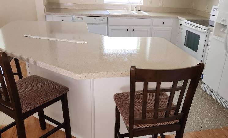 White speckled epoxy countertop on kitchen island with white cabinets and modern bar stools
