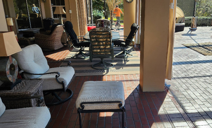 Covered patio with painted red brick floor pattern and view of outdoor seating area with wicker furniture