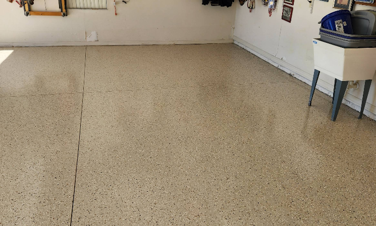 Garage interior with tan speckled epoxy floor coating showing smooth glossy finish and visible expansion joints