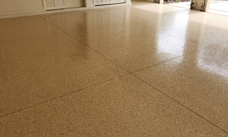 Garage with tan and brown speckled epoxy floor coating featuring high-gloss reflective surface and clean appearance