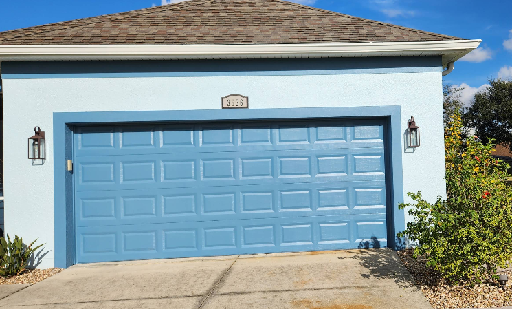 Light blue painted home exterior with blue painted garage door, white trim and decorative landscaping