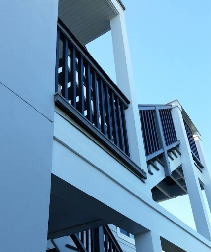 Multi-level white painted deck with black railings showing clean lines and professional finish against blue sky