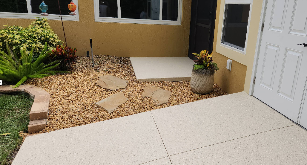 Light beige painted concrete walkway and entry area with decorative stepping stones through pea gravel