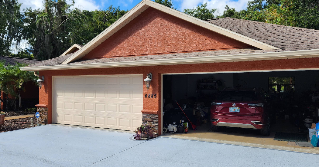 Home exterior painted in rust red with white trim and light gray painted concrete driveway