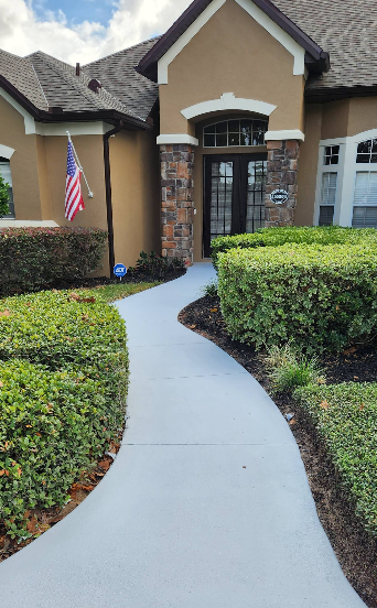 Curved white painted concrete walkway leading to home entrance with manicured landscaping