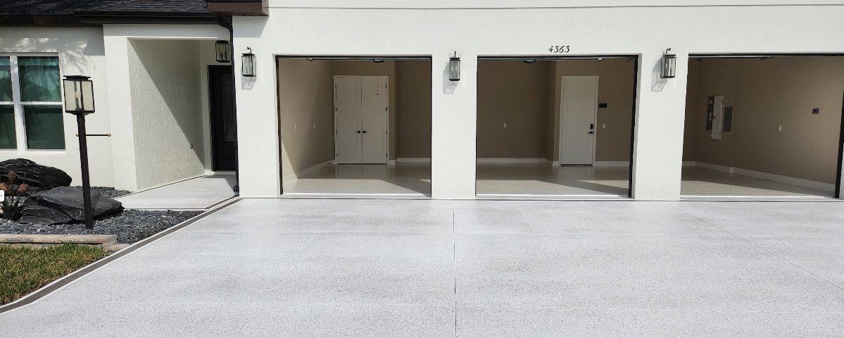 Three-car garage with light gray epoxy floor coating and white painted driveway extension