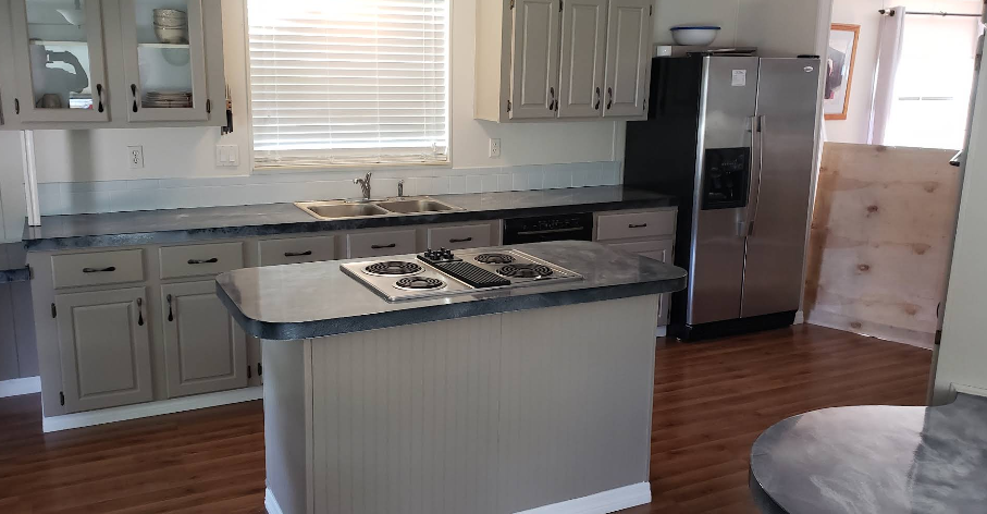 White painted kitchen cabinets with center island, dark countertops and subway tile backsplash