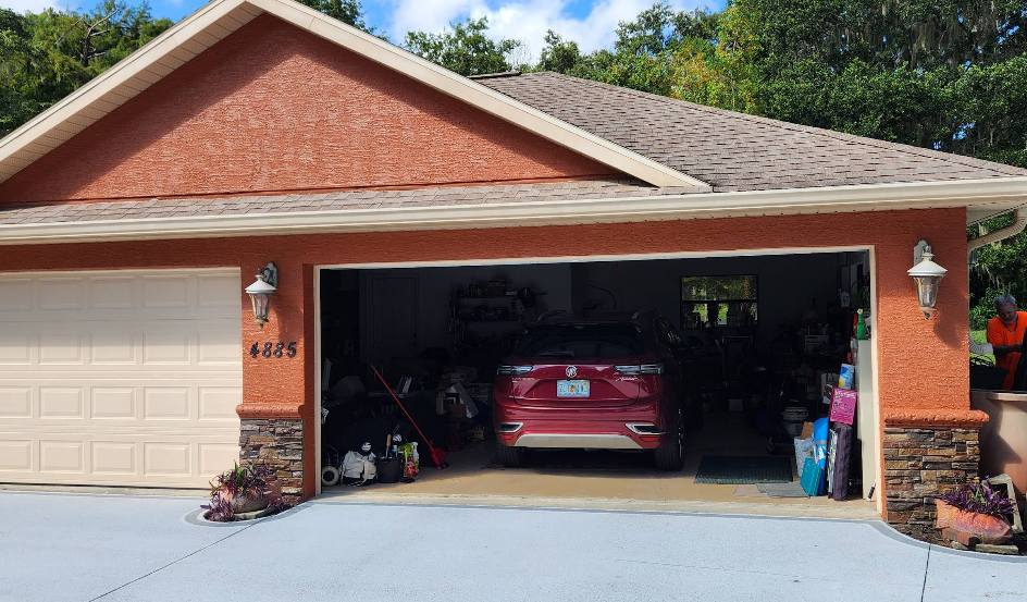 Home exterior painted rust orange with light gray painted concrete driveway and stone veneer accents