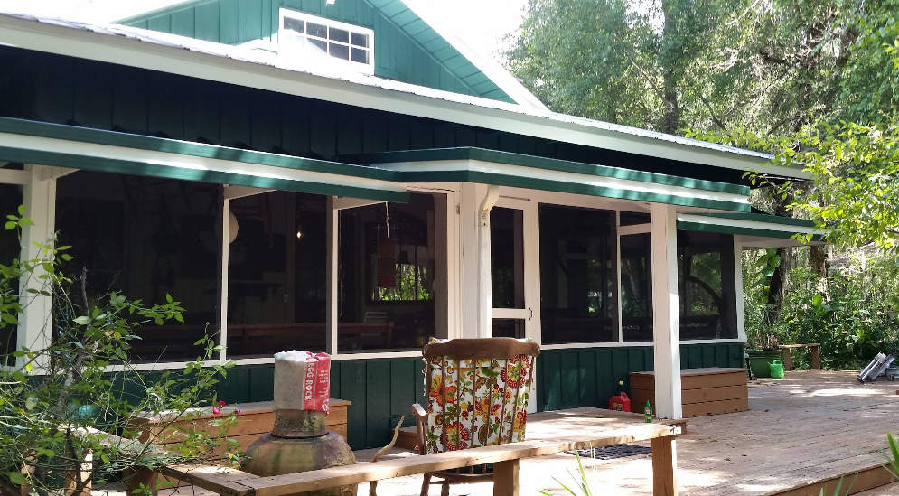 Cottage exterior painted in dark teal green with white trim and large screened windows