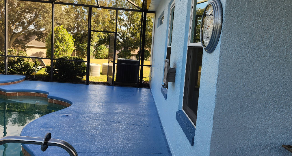 Blue painted concrete pool deck with matching painted exterior wall in screened enclosure