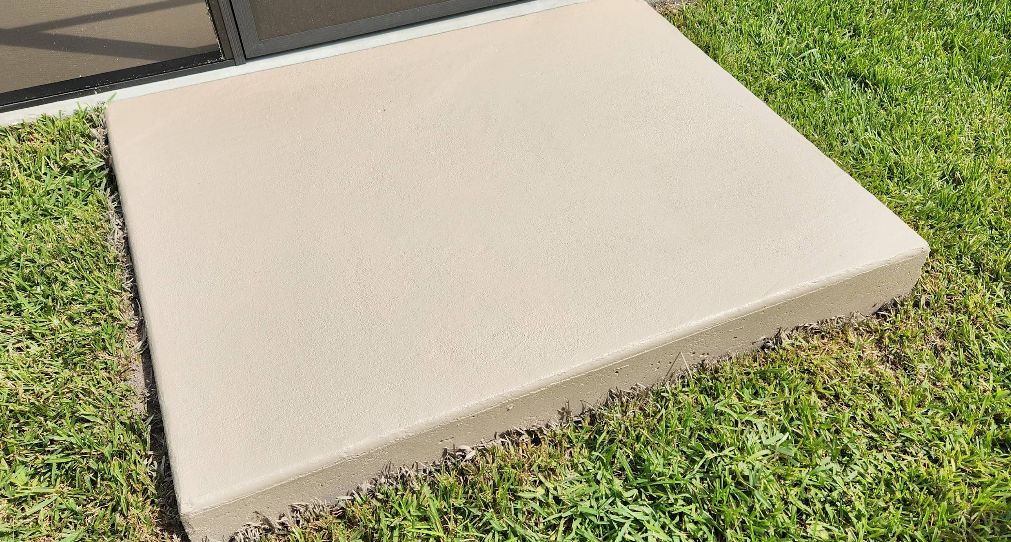 Close-up of light tan painted concrete step with smooth finish next to grass lawn