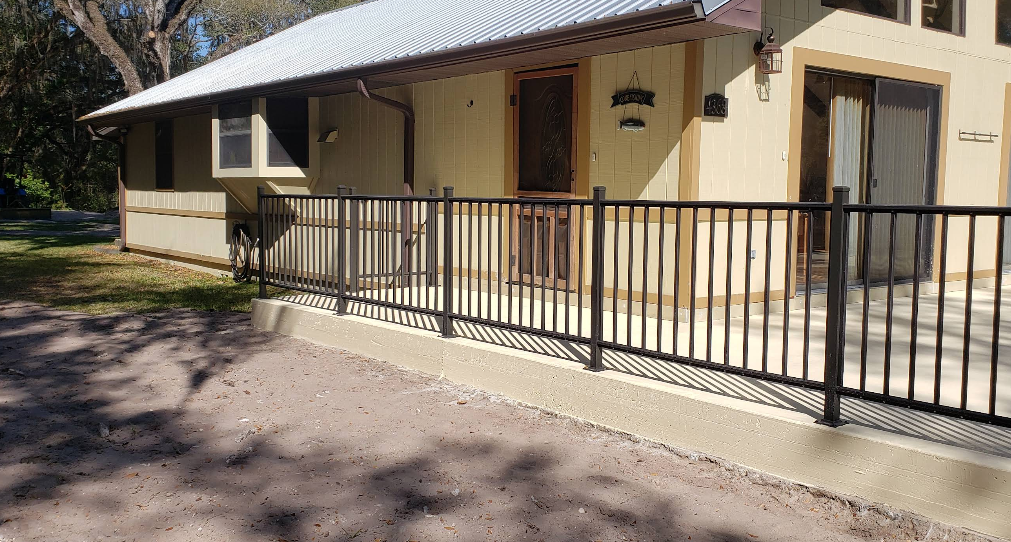 Yellow painted home with light painted concrete porch and wheelchair accessible ramp with metal railings
