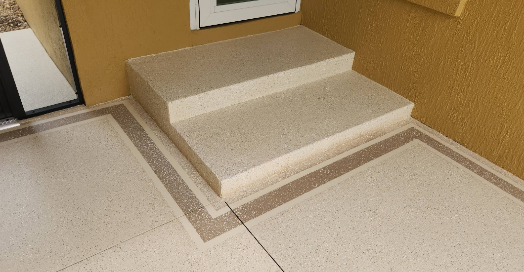 Beige speckled painted concrete steps with decorative border detail leading to doorway