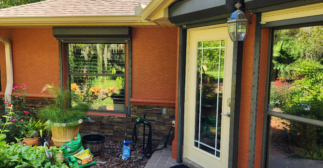 Home exterior painted in rust orange with yellow trim, stone veneer accents and potted plants