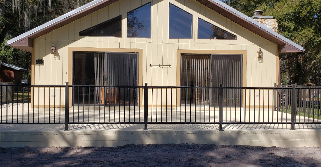 Pale yellow painted home with light gray painted concrete porch and wheelchair accessible ramp with black metal railing