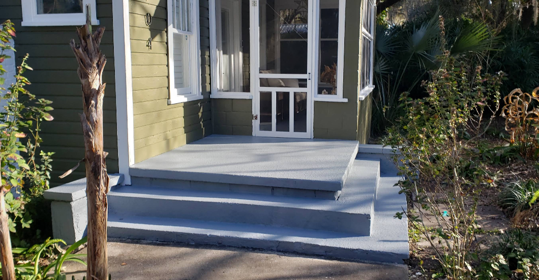 Light gray painted concrete steps and porch at home entrance with white screen door