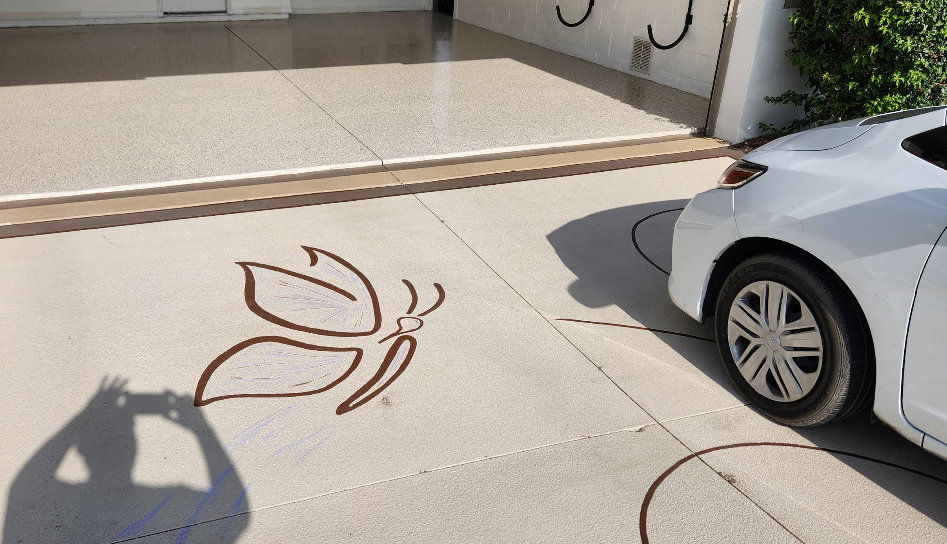 Light beige painted concrete driveway with decorative brown Browning deer logo stencil design