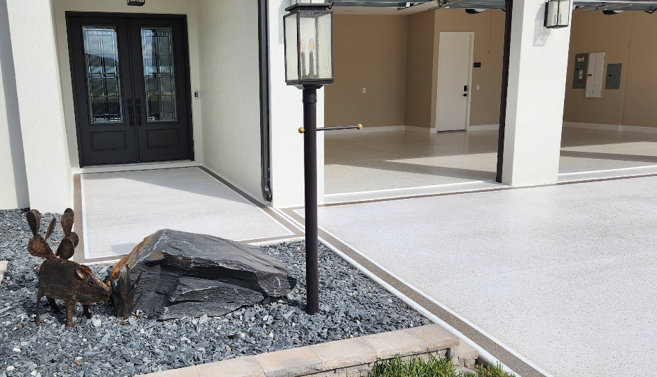 Modern white home entrance with light gray epoxy garage floor and decorative metal deer sculpture in landscaping