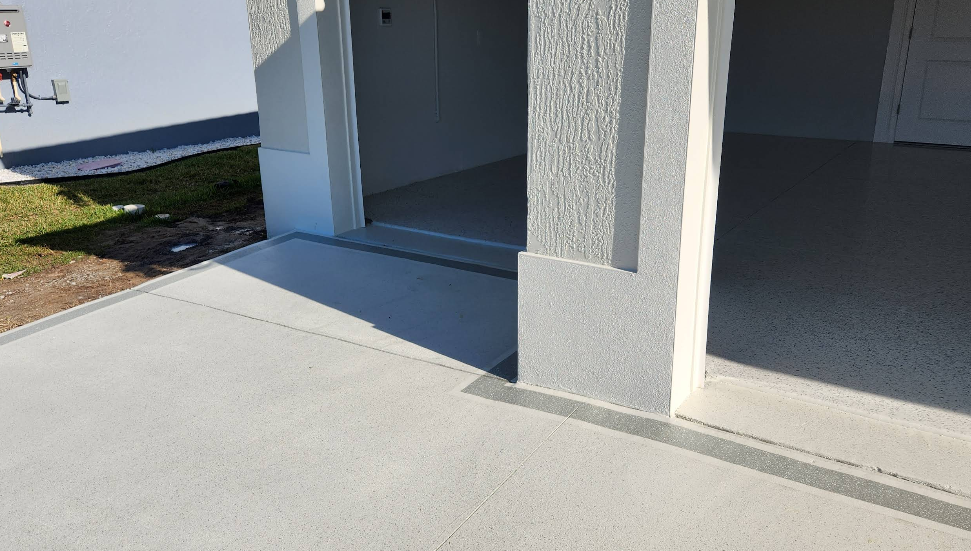Light gray painted concrete porch entrance transitioning to darker epoxy garage floor