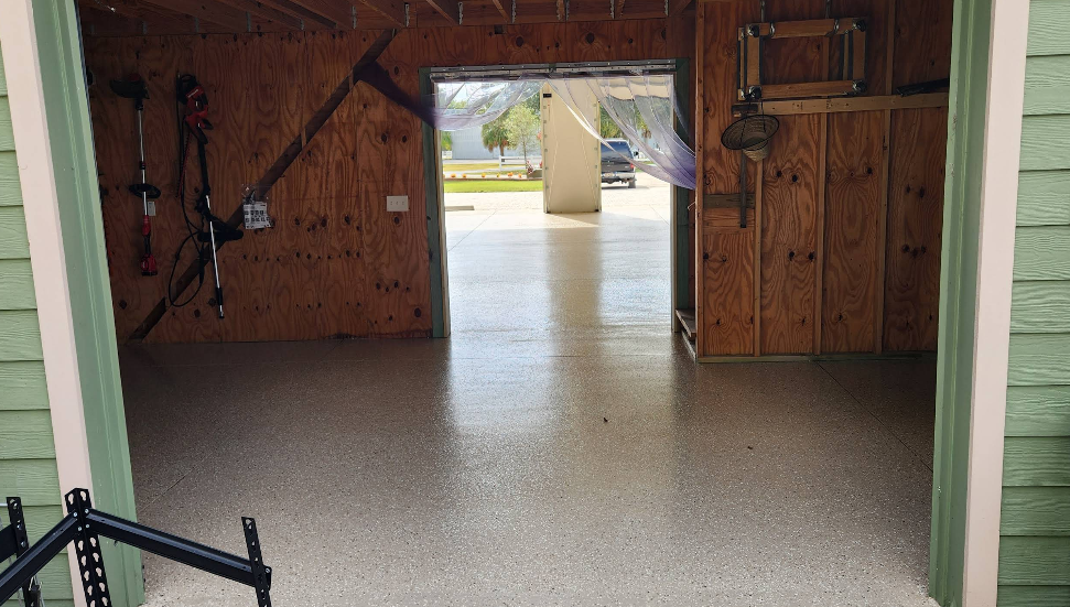 Garage interior with tan speckled epoxy floor coating, wooden walls and equipment storage