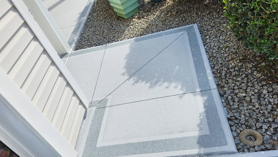 Painted concrete landing with light center and gray speckled border pattern at white home entrance