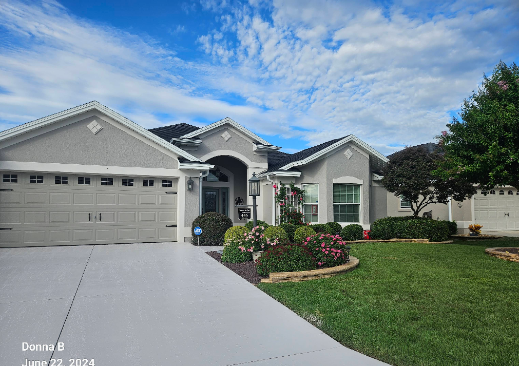 Light gray painted concrete driveway in front of well-maintained home with landscaped yard and flower beds