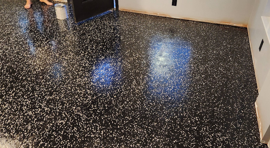 Black speckled epoxy floor coating installation in progress showing glossy reflective finish