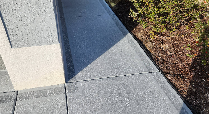 Painted concrete driveway and walkway with gray speckled border accent at white home entrance