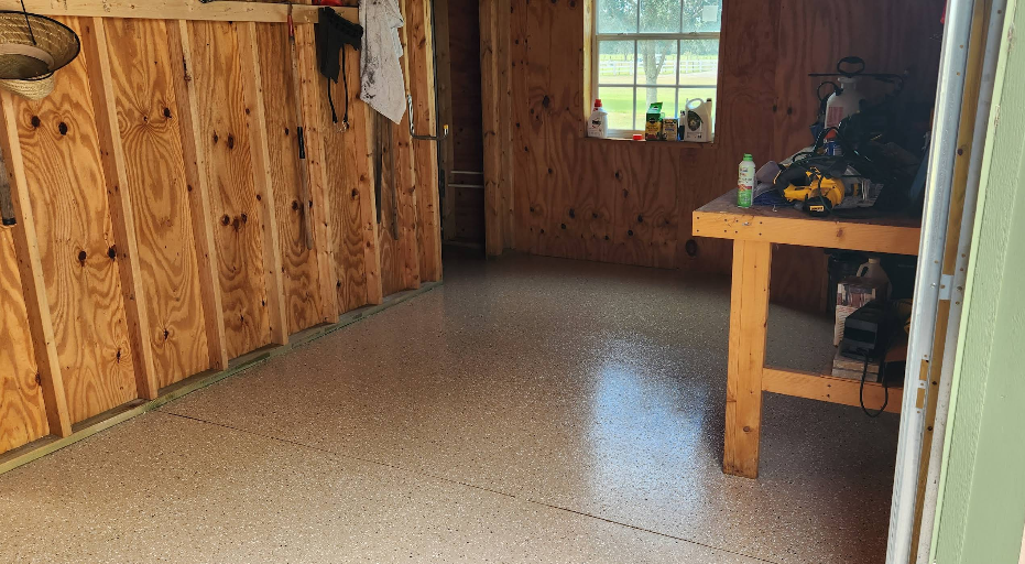 Workshop or shed interior with tan and brown speckled epoxy floor coating and wooden workbench