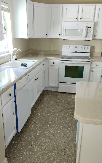 White kitchen with tan speckled epoxy floor coating and white cabinets with white appliances