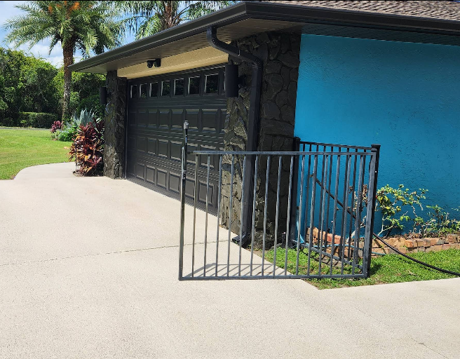 Light beige painted concrete driveway with metal railing at home painted turquoise and stone veneer