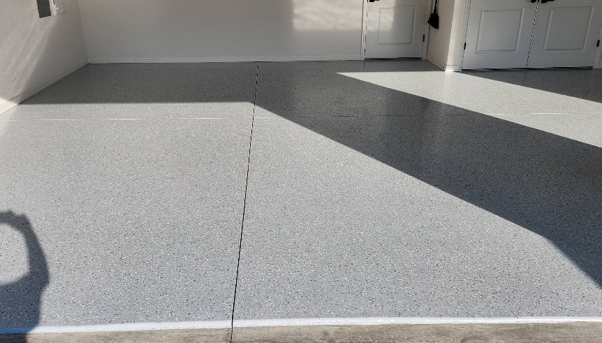 Three-car garage with two-tone gray and light speckled epoxy floor coating in geometric pattern