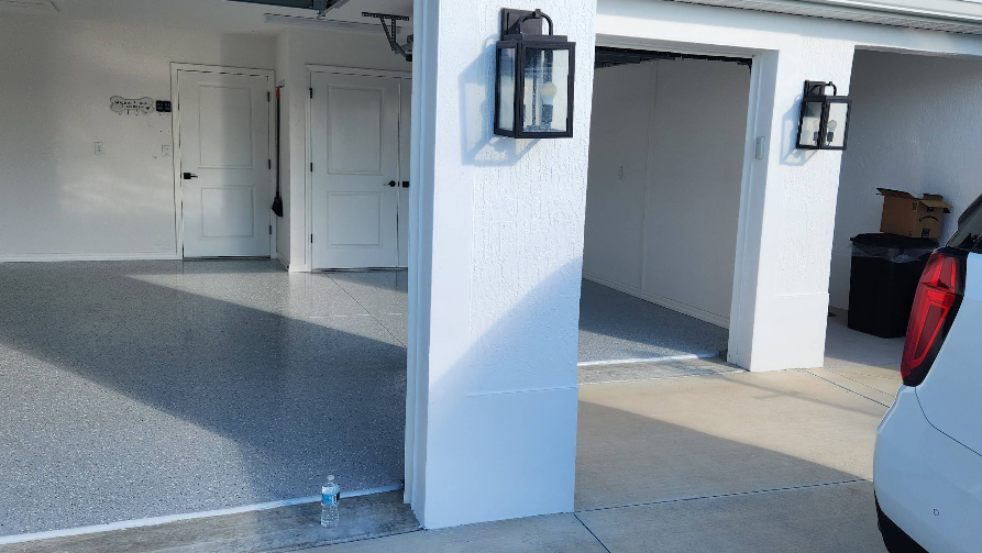 Large garage interior with gray speckled epoxy floor coating and white painted walls with modern fixtures